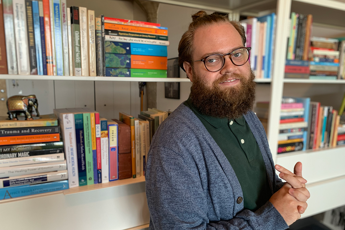 Tyler Choate standing in front of a bookshelf 