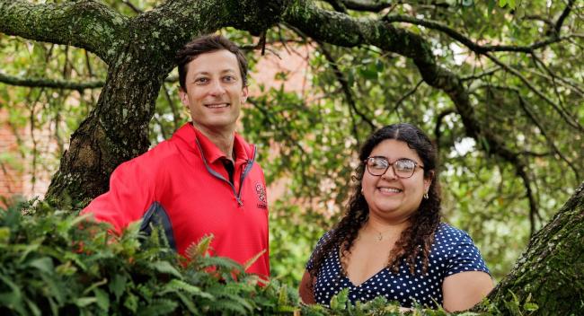 A man and a woman stand among the branches of a large, live oak tree.